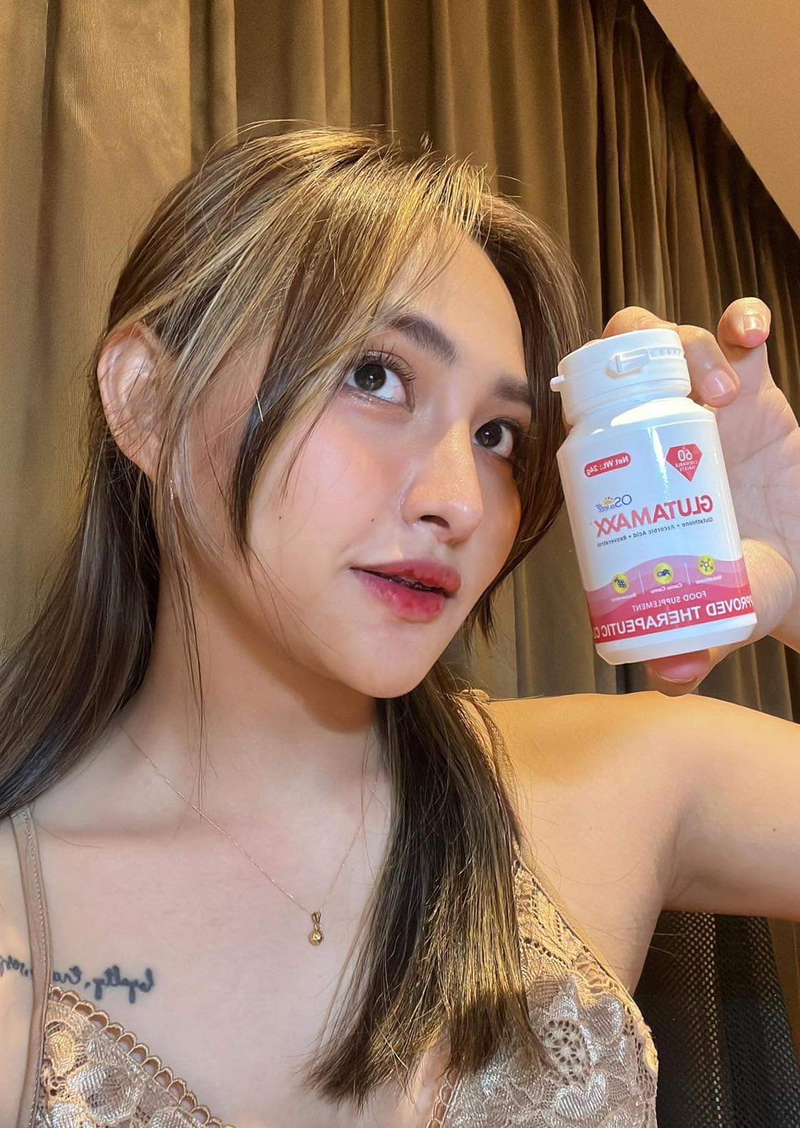 Model with radiant skin holding Gluta Maxx bottle